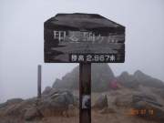 甲斐駒ヶ岳山頂と岩陰で身を守る登山者