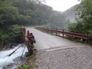 増水した川に架かる橋を渡る